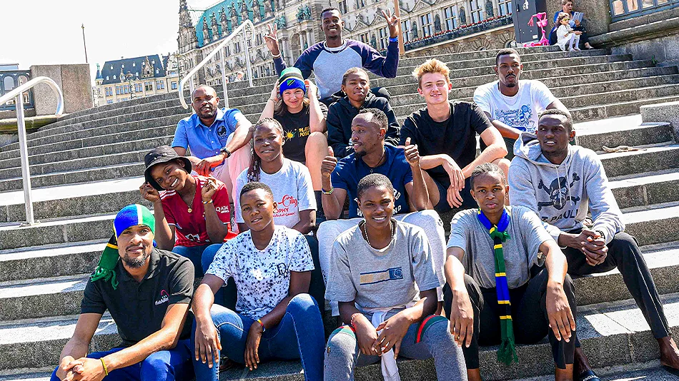 This photo shows 14 of the youth exchange participants on the steps in front of Hamburg’s city hall.
