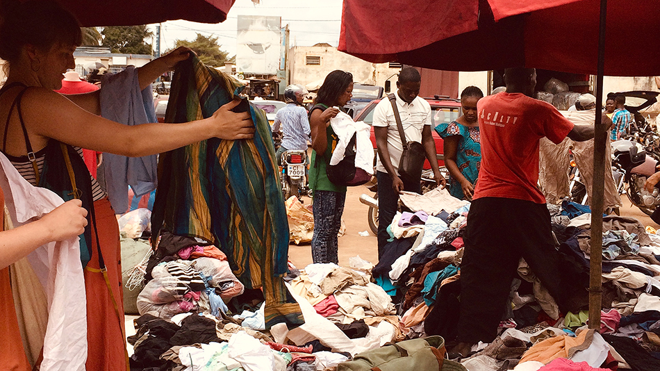 Des participant·e·s achètent sur le marché des vêtements et des tissus pour les costumes et décors des représentations théâtrales.