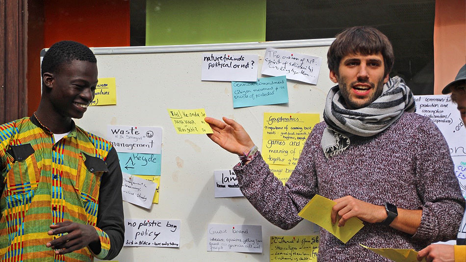 Deux participants se tiennent devant un écran et présentent les idées recueillies.