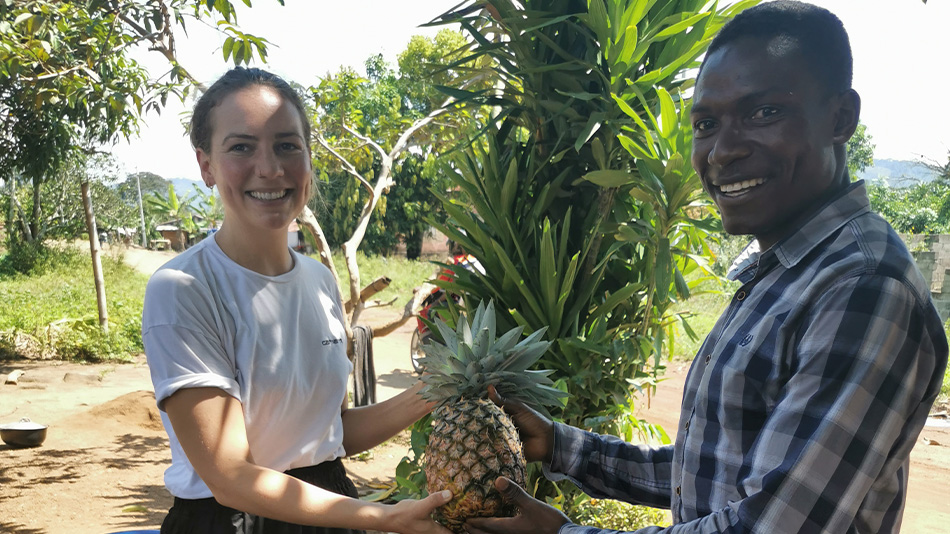 Das Foto zeigt Marlena und einen jungen Mann. Sie halten gemeinsam eine Ananas und lächeln in die Kamera.