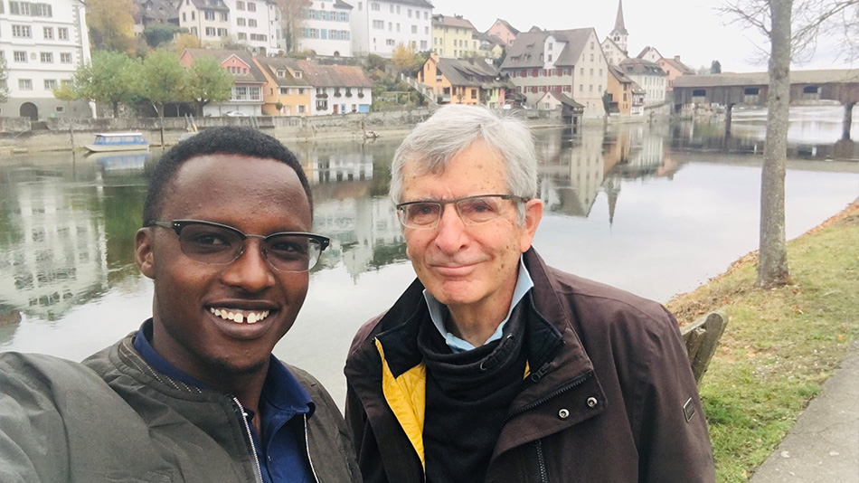 Das Foto zeigt Ole und seinen Tandem-Partner, den SES-Experten Dr. Willy Zink. Sie machen ein gemeinsames Selfie vor dem Rhein und lächeln in die Kamera.