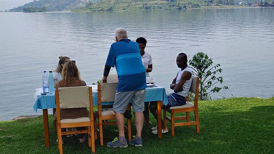 Idyllische Szene am See: Laura, Andreas Nommels und drei Kolleg*innen sitzen an einem bedeckten Tisch am Lake Kivu.