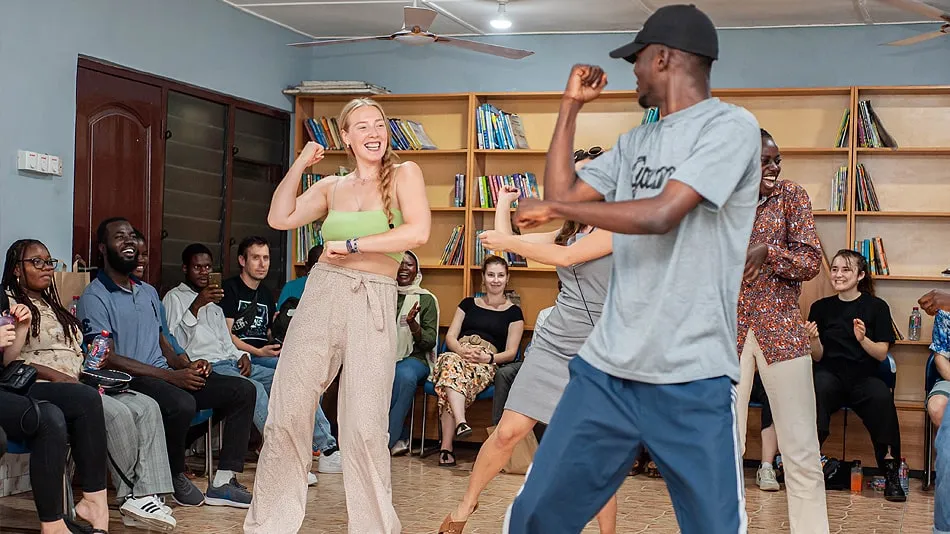 Das Bild zeigt eine Gruppe von Workshop-Teilnehmenden beim Tanzen bei der Organisation DUNK Grassroots. Im Vordergrund sieht man den Tanzlehrer.